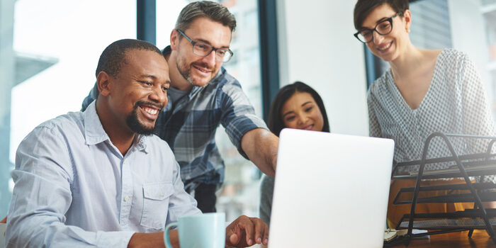 Cropped shot of a group of colleagues working together on a laptop in a modern office